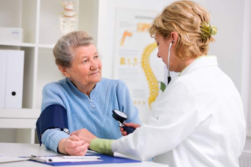 GP doctor measuring blood pressure in older female patient