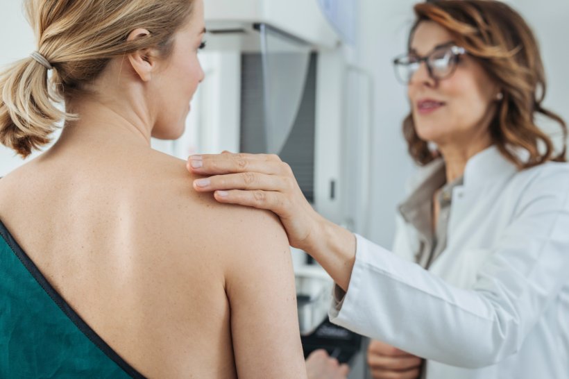 breast cancer examination, female physician puts her hand on the shoulder of...