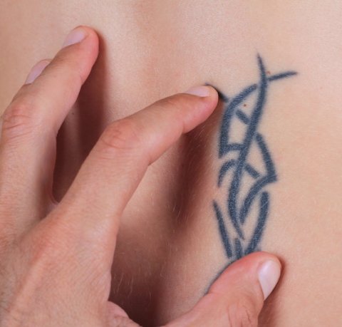 closeup of hand examining tribal tattoo on skin