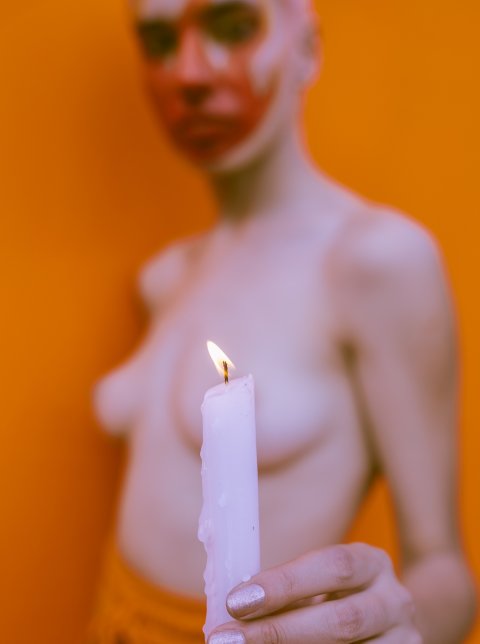 shallow focus photo of topless woman holding a candle