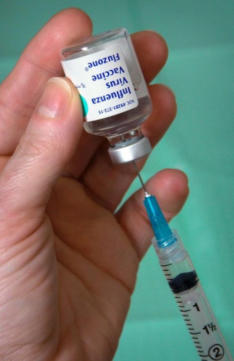 flu vaccine serum extracted from vial into a syringe