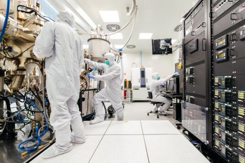 people in white safety uniforms in a high-tech factory setting