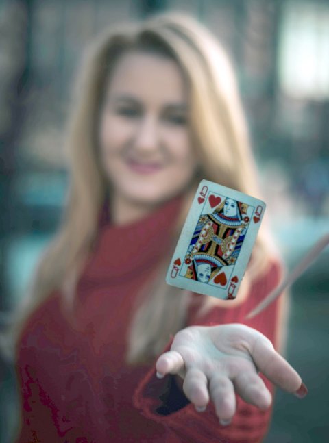 woman holding queen of hearts playing card above her hand
