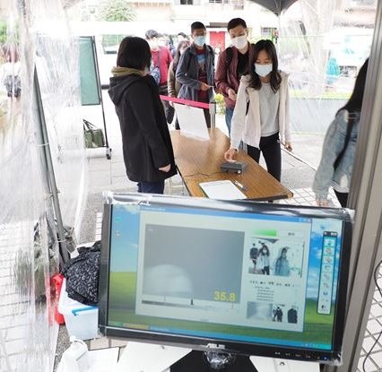 people wearing face masks queueing in front of hospital entrance in taiwan