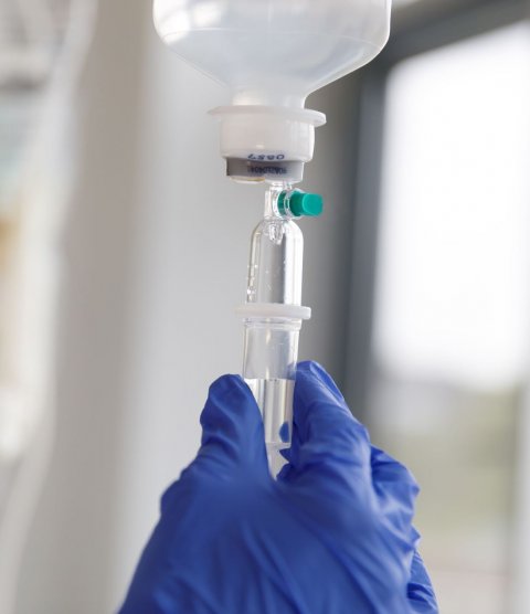 medical professional in blue rubber gloves checking IV bag