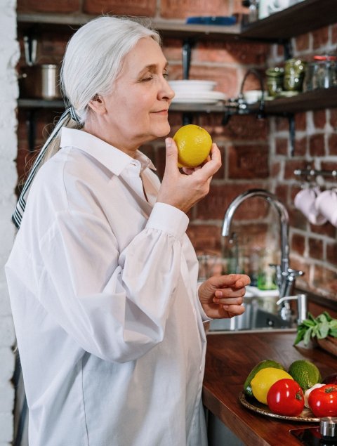 older woman holding and smelling a lemon
