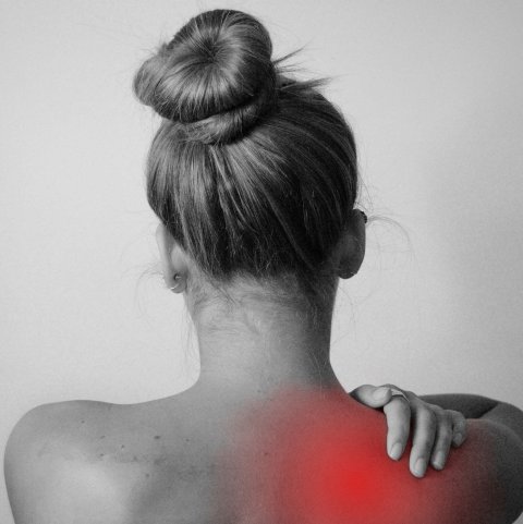 grayscale image of woman holding her shoulder in pain