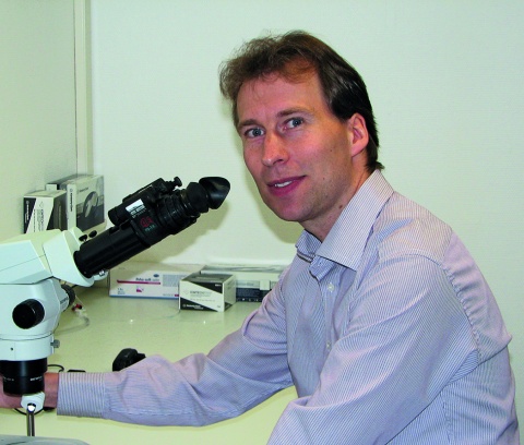 Tim Gollisch sitzend an einem Mikroskop
