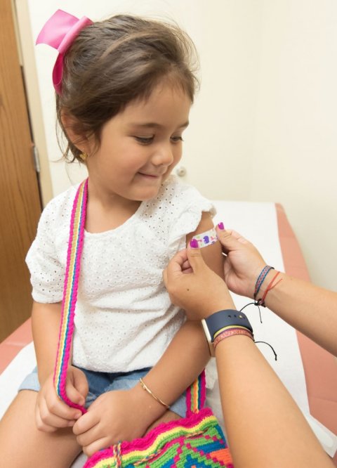 young girl receiving band-aid on her arm after vaccination
