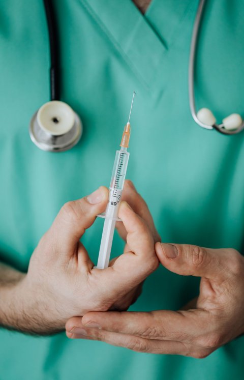 man in green hospital staff robe holding syringe