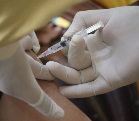 closeup of vaccine syringe in patient's arm