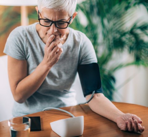 elderly woman measuring blood pressure at home