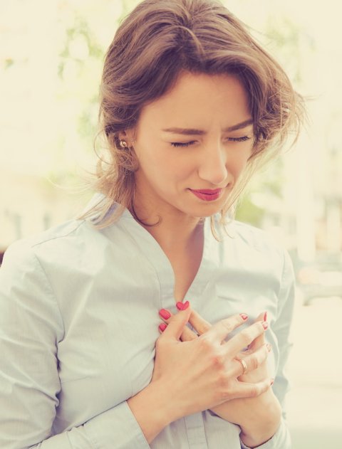 young woman holding her chest from heart pain