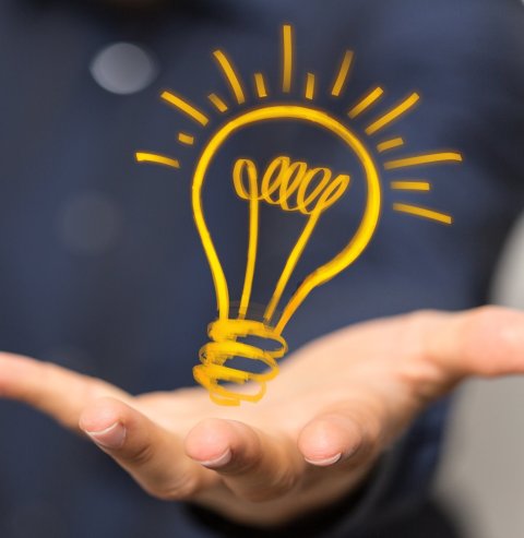 closeup of hand holding lightbulb illustration as symbol for innovation, ideas