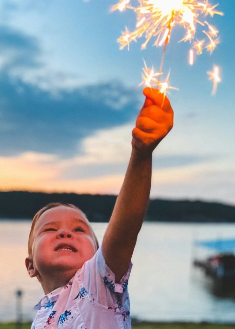 young boy holding sparkler in one hand
