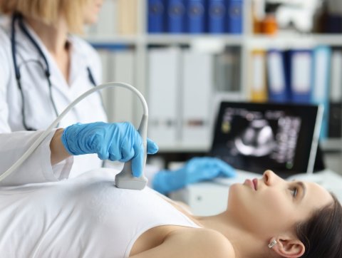 Sonography expert examines the breast of her patient with ultrasound probe