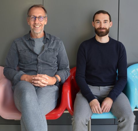 Andreas Villunger and Dario Rizzotto sitting next to each other on colorful chairs, facing the camera