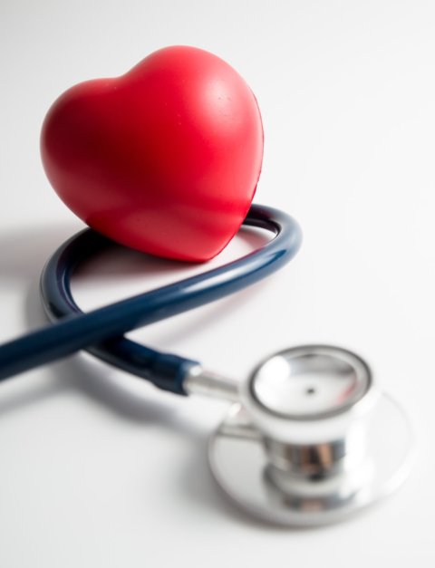 Red heart lying on top of a stethoscope