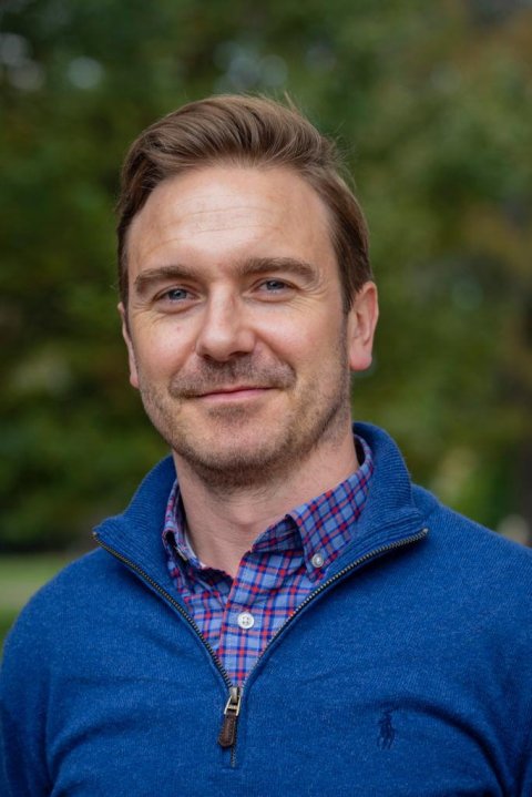 Portrait photo of Brian Conlon, PhD, in front of a blurry green background