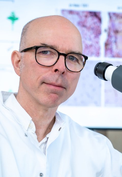 Portraitfoto von Prof. Markus Otto neben einem Mikroskop