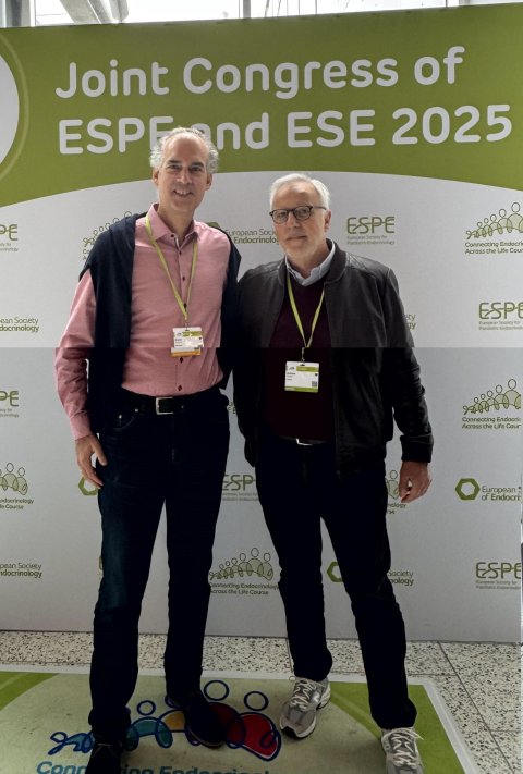 Prof. Martin Fassnacht und Prof. Antoine Tabarin stehen vor einer Fotowand auf einem Endokrinologie-Kongress