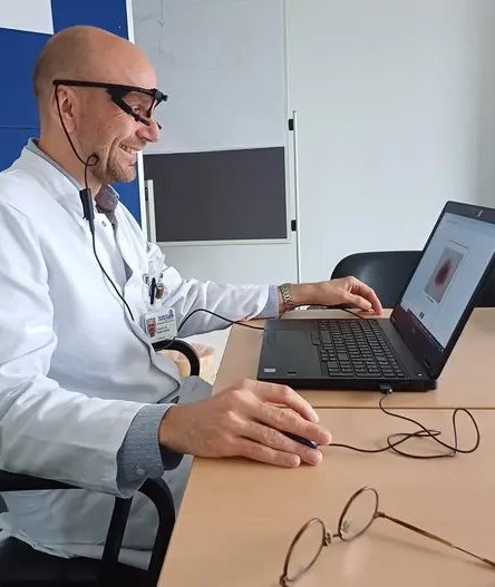 Bastian Schilling sitzt an einem Tisch und bedient einen Laptop