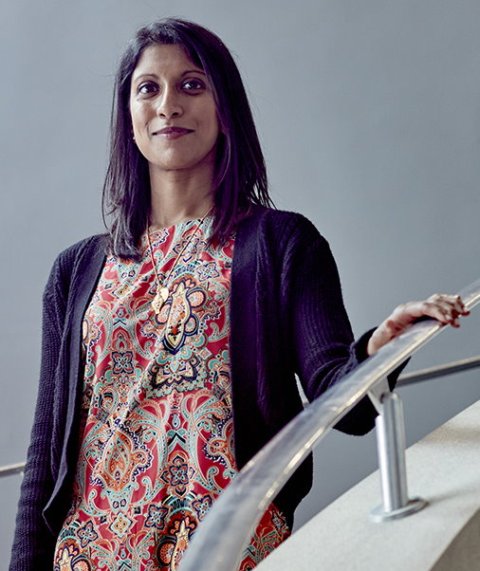 Dr Shaarna Shanmugavadivel is standing on a flight of stairs, holding the handrail