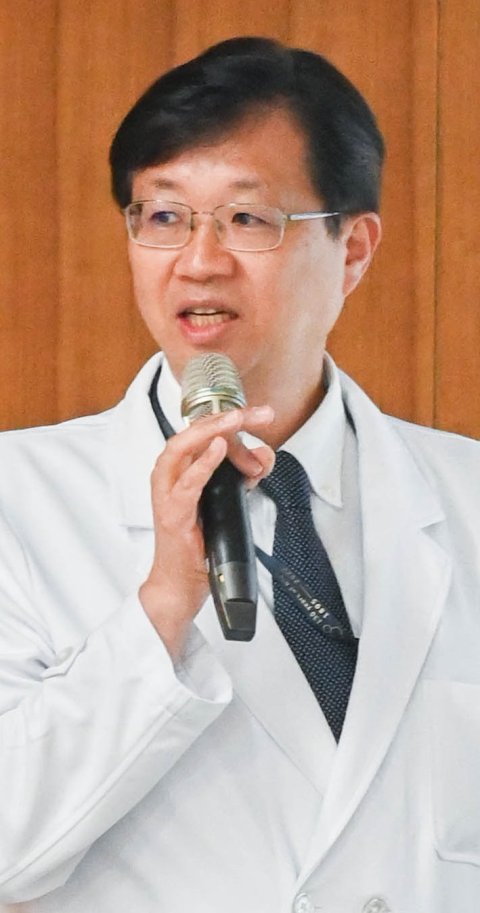 Professor Han-Mo Chiu holding a microphone during a presentation