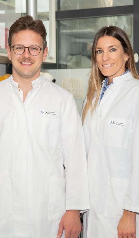 Timo Mohr und Miriam Schiffer stehen in weißen Arztkitteln in einem Raum mit elektrischen Geräten