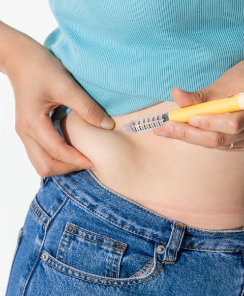 Eine Frau verabreicht sich selbst eine Spritze mit einem Medikament gegen Diabetes oder Übergewicht