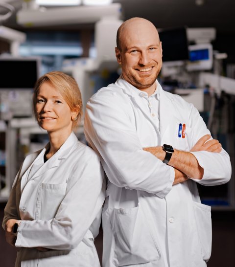 Carolin Steinack und Thomas Gaisl stehen mit dem Rücken zueinander in einem OP-Saal