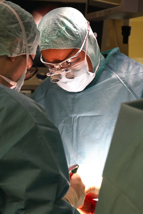 Prof. Steven Warmann steht in OP-Kleidung während einer Operation über dem Patienten, der nicht im Bild zu sehen ist. Ihm gegenüber steht ein weiterer Chirurg, beide blicken nach unten auf den Patienten