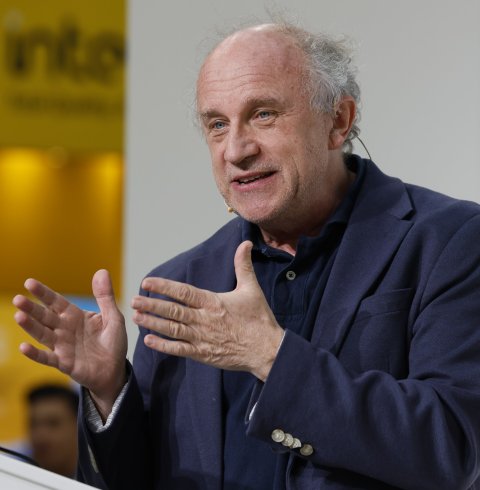Prof. Paul Lukowicz steht hinter einem Rednerpult und gestikuliert mit seinen Händen