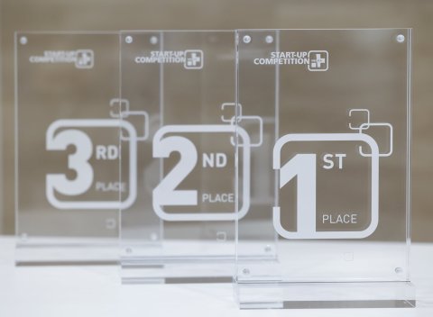 Drei Trophäen in Form transparenter Rechtecke, beschriftet mit den Platzierungen 1, 2 und 3