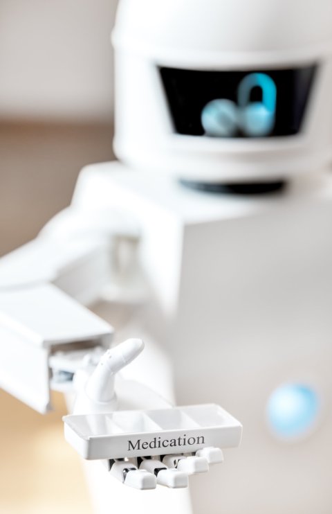 A cute white robot is offering a medicine dispenser with his robotic hand. Concept of what a robot for home care can look like