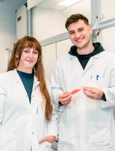 Johanna Trommer und Tobias Krönke stehen in weißen Laborkitteln nebeneinander in einem Labor