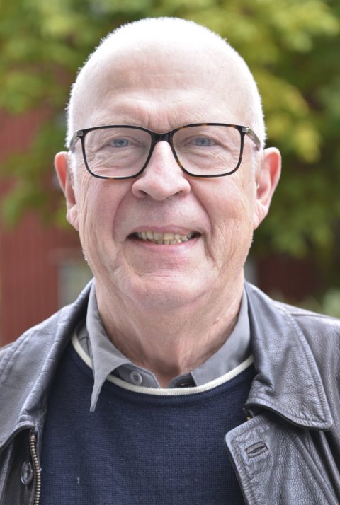 Portrait photo of Tomas Olsson. Blurry in the backgound, trees with green leaves can be seen