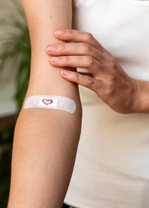 The right arm of a woman, with a band-aid with a heart on it