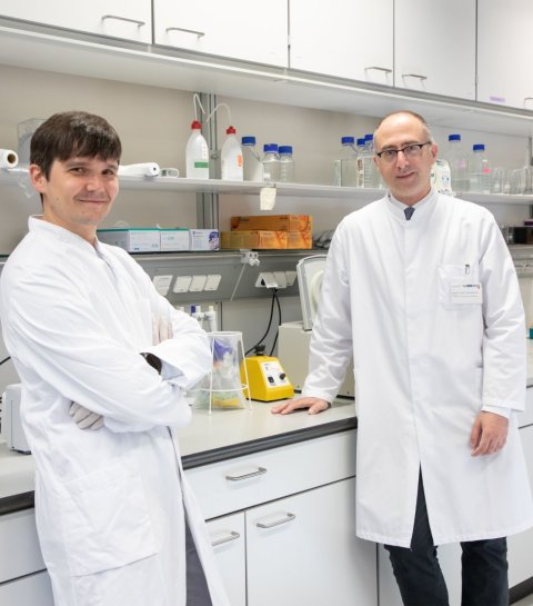 Zwei Wissenschaftler im weißen Laborkittel stehen in einem Labor