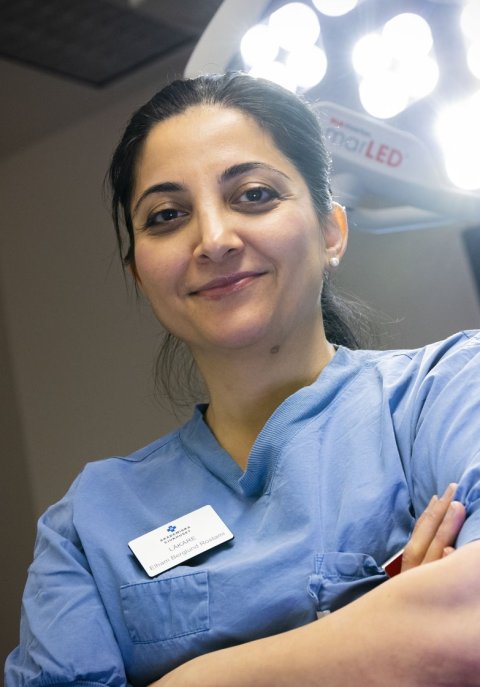 Elham Rostami is standing in front of a surgical light, with her arms crossed in front of her chest