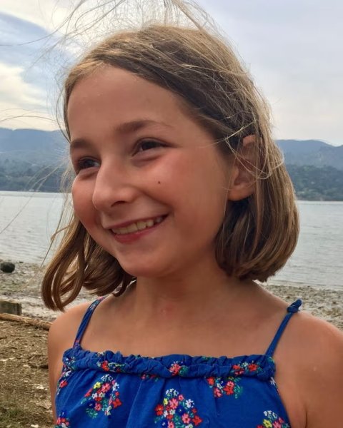 Foto des jungen Mädchens Martha Mills am Stand. Im Hintergrund ist ein See zu erkennen