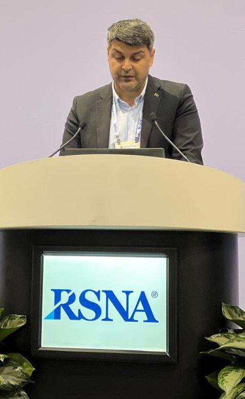 Dr. Elshan Abdullayev is standing behind a speaker's podium