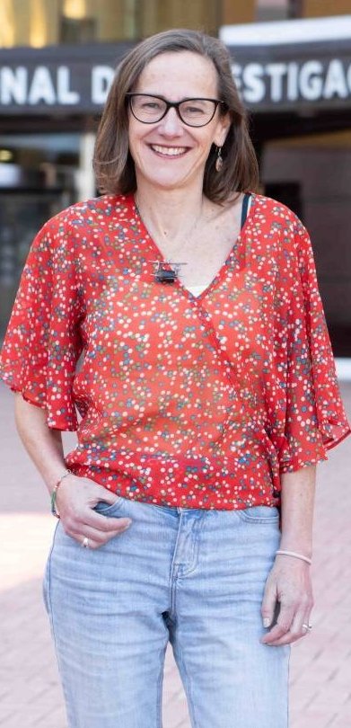 Eva González-Suárez is standing in front of a CNIO building, smiling at the camera