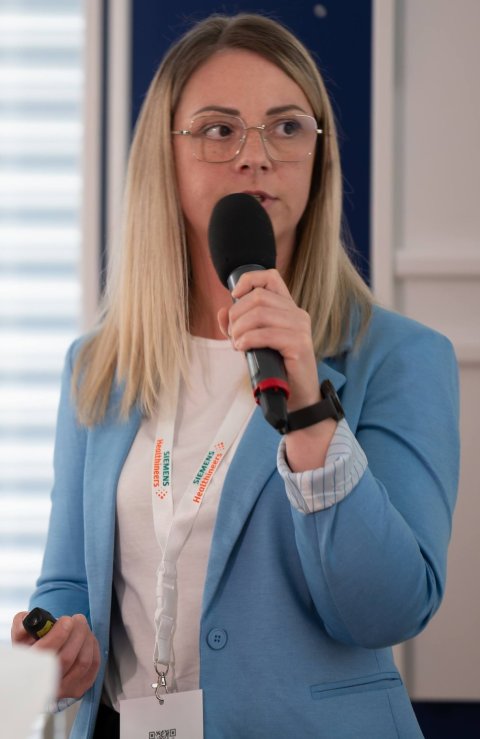 Monika Städtler hält eine Vortrag auf einem Fachkongress für Radiotechnologen. Sie spricht in ein Mikrofon, das sie in der rechten Hand hält