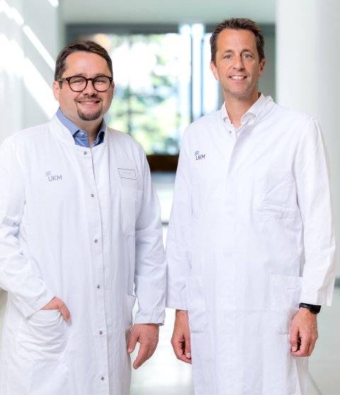 Prof. Dr. Jan Rossaint und Prof. Dr. Alexander Zarbock stehen im hellen Flur eines Krankenhauses