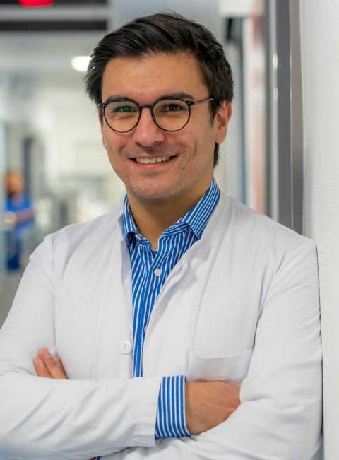 Dr. Dr. Emre Kocakavuk steht mit verschränkten Armen im Krankenhausflur