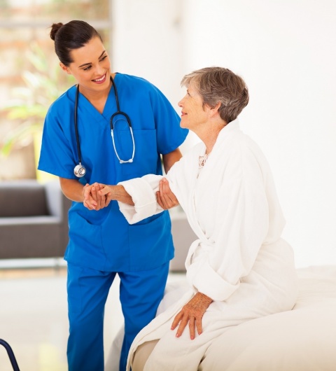 young female caregiver helping senior woman getting up